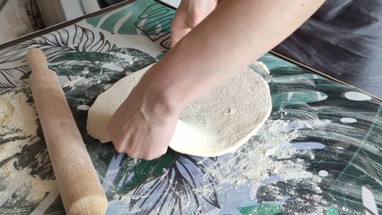 Woman rolling out dough with a rolling pin on the table