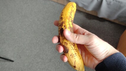 Man holding a ripe banana in his hand