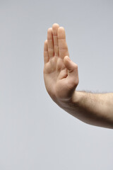 Vertical closeup studio shot of unrecognizable male hand showing gesture refusal and rejection,...