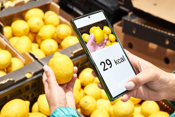 Checking calories on lemon in store with smartphone