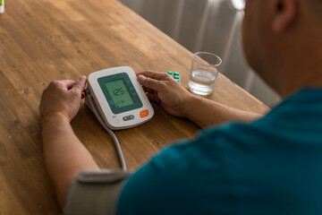 Seniory man checks blood pressure with monitor on upper arm in room smiling elderly gentleman...