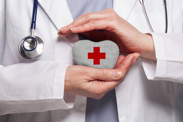 Doctor holding heart with Red cross symbol on white background. Healthcare, charity, insurance and...