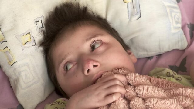 Authentic shot of a teenage girl with Down syndrome, autism. The loving hand of an adult strokes her cheek. Concept: disabled people, child care, healthcare, disability, dreams, life, hope.