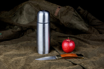 Vacuum Flask with Apple and Knife on an Outdoor Coat - 789190857