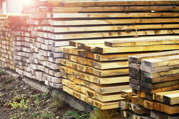Stack of fresh pine boards in a sawmill warehouse. Harvesting, sale of lumber for construction - obrazy, fototapety, plakaty