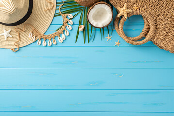 Top view of essential summer holiday accessories on a bright blue wooden background. Includes hat,...