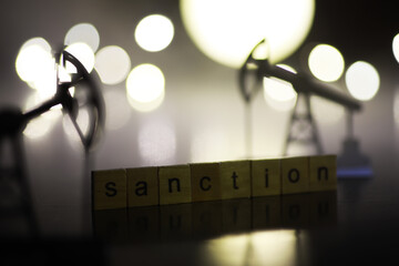 Word Sanctions made of wooden block letters with dramatic lighting and smoke