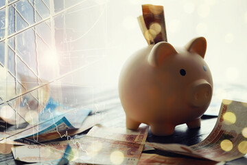 A piggy bank in the form of a pink pig stands on the wooden table with russians money, inscription...