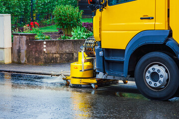 Removing oil spills. Yellow Truck remove engine oil from a street. oil spilling on the road in a residential district. Oil Spill Clean Up by vehicle. close-up of front of truck