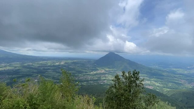 Landscape Timelapse of Mount Andong (Grabag, Magelang, Jawa Tengah, Indonesia) with a lot of clouds, green scape, villages, trees, forest etc. Taken from the peak of Mt. Telomoyo (Ngablak, Magelang)