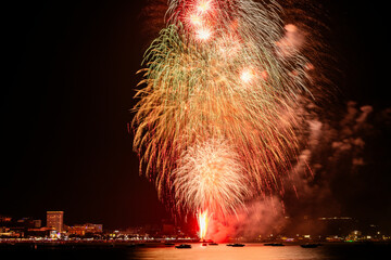 Mesmerizing display of fireworks explodes in the night, illuminating the waterfront with a tapestry...