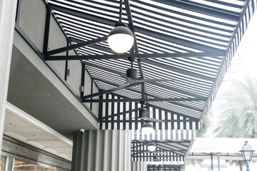 Empty Cafe tables and chairs outside in European Restaurants with black and white striped awning...