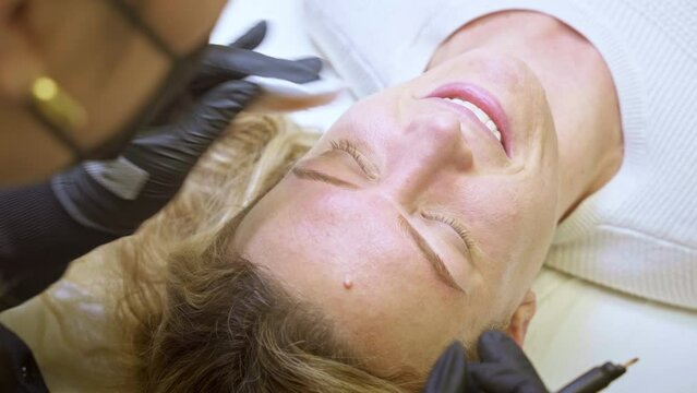 Beautician performing microblading on a client's eyebrows