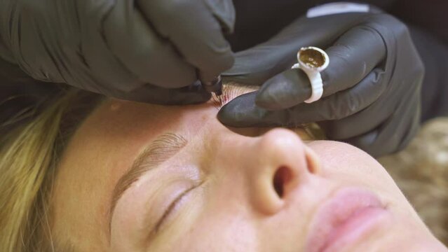 Beautician performing microblading treatment on client