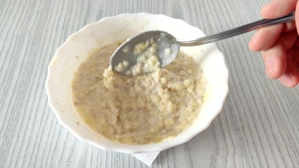 Unrecognizable person stirs oatmeal with millet with a spoon