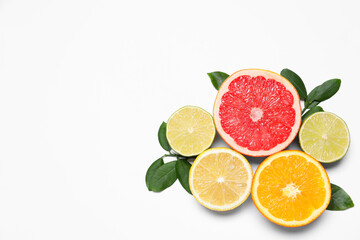 Different cut citrus fruits and leaves on white table, flat lay. Space for text