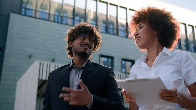 Business partners in city with contract document diverse colleagues talking discuss urban building developer architect realtor skyscrapers real estate expert woman consult man client buyer development