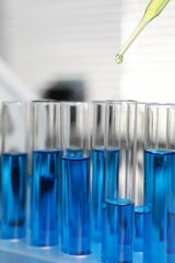 Laboratory analysis. Dripping liquid into test tubes indoors, closeup