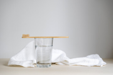 Wooden toothbrush on glass with drinking water against cotton and fresh face towel