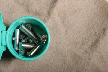 Used finger batteries in a miniature trash can. on a beige dirty background. Recycling of waste.