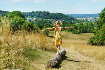 Cute girl in dress walks on the grass barefoot - obrazy, fototapety, plakaty