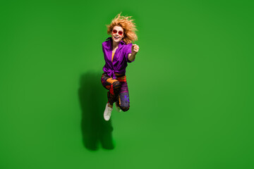 Photo portrait of pretty young girl jump running hurry wear trendy purple outfit isolated on green color background