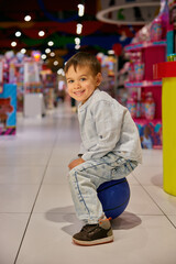 Portrait of happy excited boy child sitting on ball during shopping in mall - 789227061