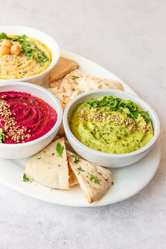 Trio of Hummus Varieties with Pita Bread on White Plate