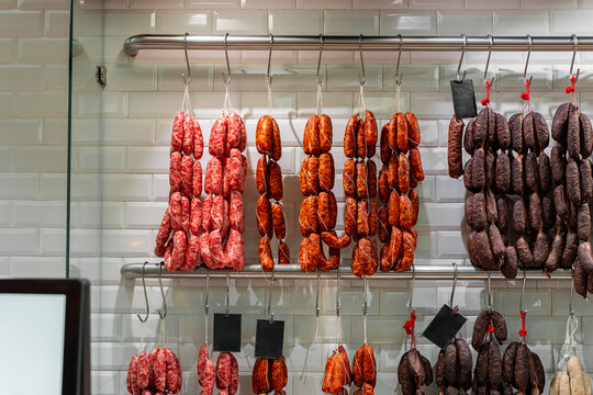 Assorted cured meats hanging in a delicatessen shop