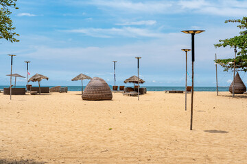 Empty sandy beach with yellow sand in sunny weather on which there are sun umbrellas and sun loungers and beach furniture.	