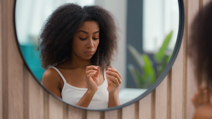 Worried beautiful sad upset African American woman girl female lady looking at mirror reflection...