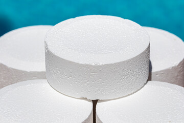 Pool chlorine tablet for pool maintenance in the form of round tablets to keep the water clean in summer before swimming - obrazy, fototapety, plakaty