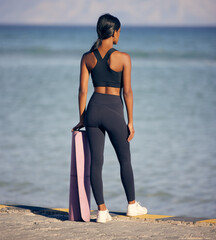 Woman, fitness and peace with yoga mat at beach for outdoor workout, exercise or training in nature. Rear view of female person ready with equipment for balance in health and wellness by ocean coast