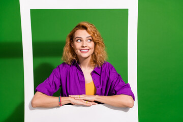 Photo of lovely young lady lean on instant photo frame look empty space dressed stylish violet clothes isolated on green color background