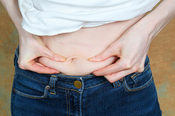 Bloated woman holding belly fat on her stomach