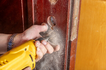 man drilling holes and installing a lock on the door - obrazy, fototapety, plakaty