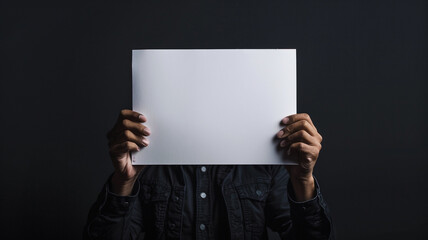 A man holding up an empty white sheet paper on black background