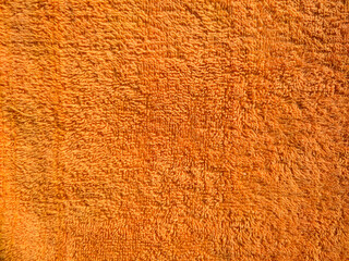 Bright orange colour terry bath towel. Soft terry cotton fabric, cloth. Blank genetic orange towel rug. Orange towel seamless texture, abstract background. Landscape photo