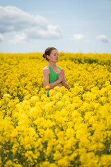 Woman meditating in a yellow rapeseed field, springtime. de-stressing from everyday life.