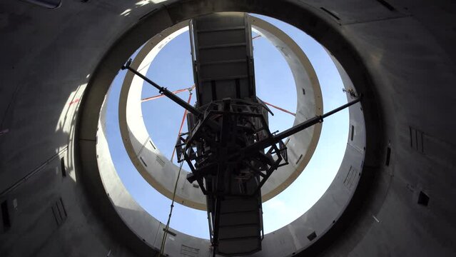 Timelapse of a wind turbine tower construction showing a crane stacking concete components filmed from the inside of the tower while it being built low angle shot round building inside a grain silo 4K