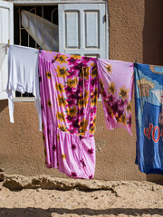 du linge sèche suspendu à une corde dans une rue de la vieille ville de Saint louis du Sénégal en Afrique - obrazy, fototapety, plakaty