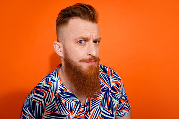 Photo of unsure suspicious guy dressed print shirt looking you empty space isolated orange color background