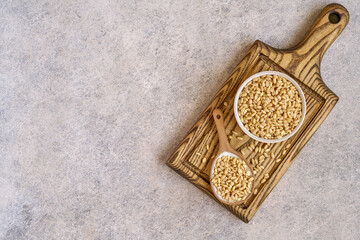 Wheat grains  in ceramic bowl  and spoon on wooden board. Top view