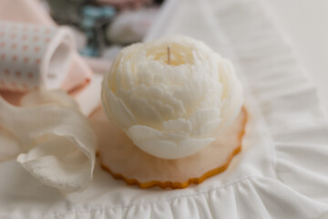 handmade candle in the shape of a flower on a light background, space for text