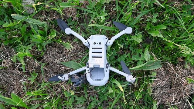 Crashed and damaged drone. Broken arms and camera gimbal of drone on grass. Drone fell to the ground. Accident during flight.  