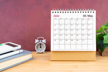 May Monthly desk calendar for 2024 year and calculator on wooden table.