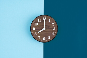 Wooden clock placed in middle of blue background.