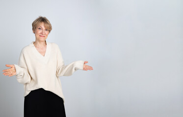 Portrait of emotional woman. Confident woman showing direction with hand on light gray background. Looking at camera, banner. High quality photo