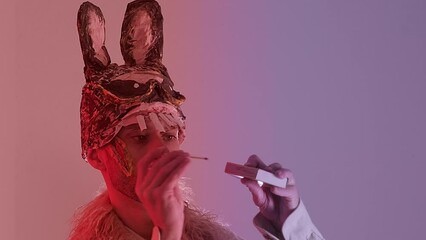 scary maniac man, young guy in cringe in scary bunny mask lights match, looks at fire, pyromania concept, theme of fear and horror, concept run while match burns, Halloween and Festive Costumes