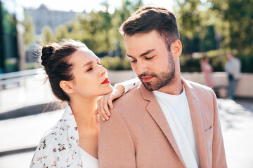 Beautiful fashion woman and her handsome elegant boyfriend in beige suit. Sexy brunette model in summer clothes. Fashionable smiling couple posing in street Europe. Brutal man and female outdoors